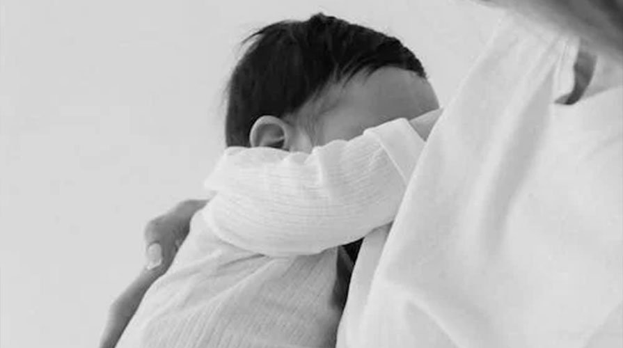 foto em preto e branco do filho no colo da mãe