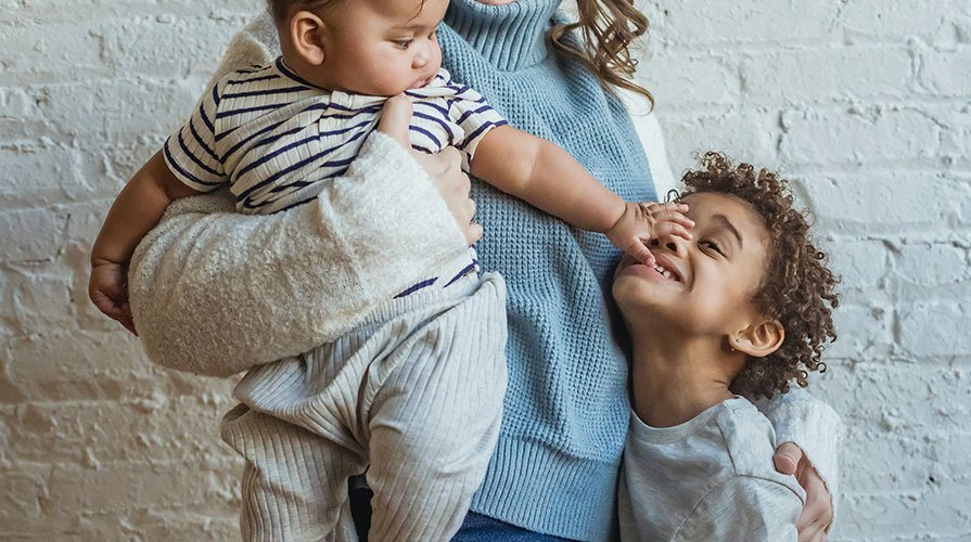 mãe tentando segurar dois filhos