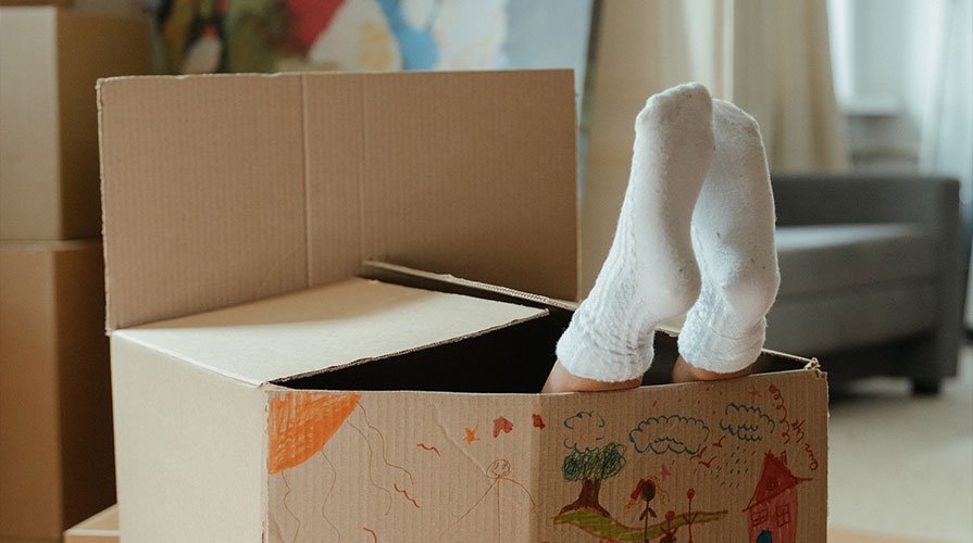 criança dentro de uma caixa de papelão decorada, só com os pés a mostra