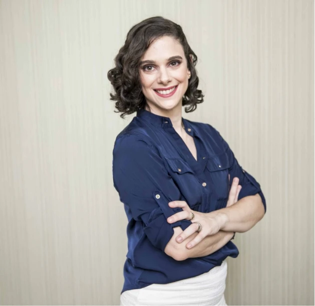 Paula em pé de braços cruzados