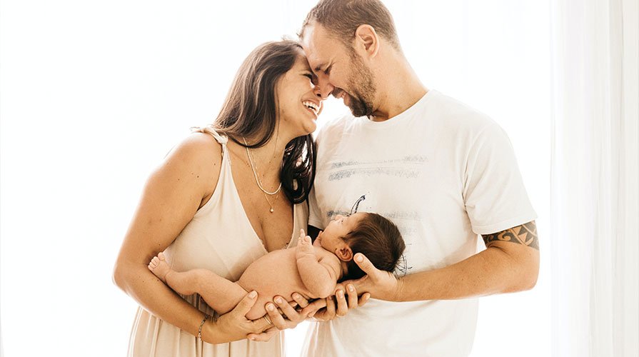 Mãe e pai felizes segurando o bebê