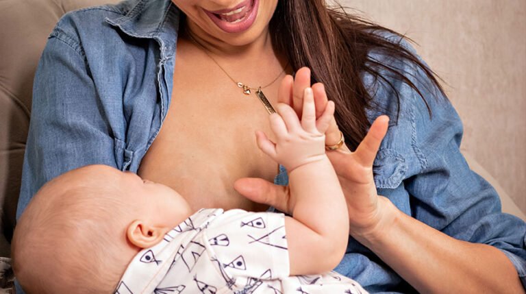mãe amamentando bebê e brincando com sua mão
