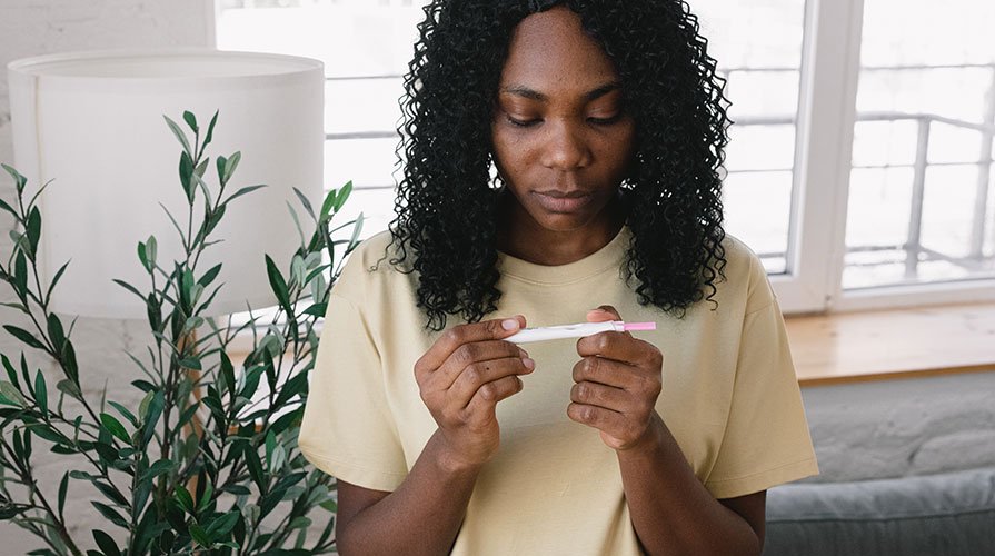 mulher olhando teste de gravidez